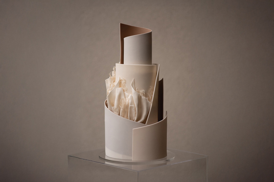 A neutral coloured, tiered cake with signature YiShi Cake ruffles